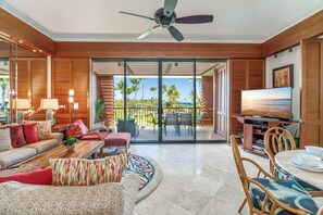 Un salón amplio con un televisor grande, asientos cómodos y vistas al exterior.