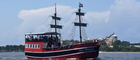 Un navire rouge et noir, nommé Sea Dragon, avec un pavillon hissé, naviguant sur l’eau.