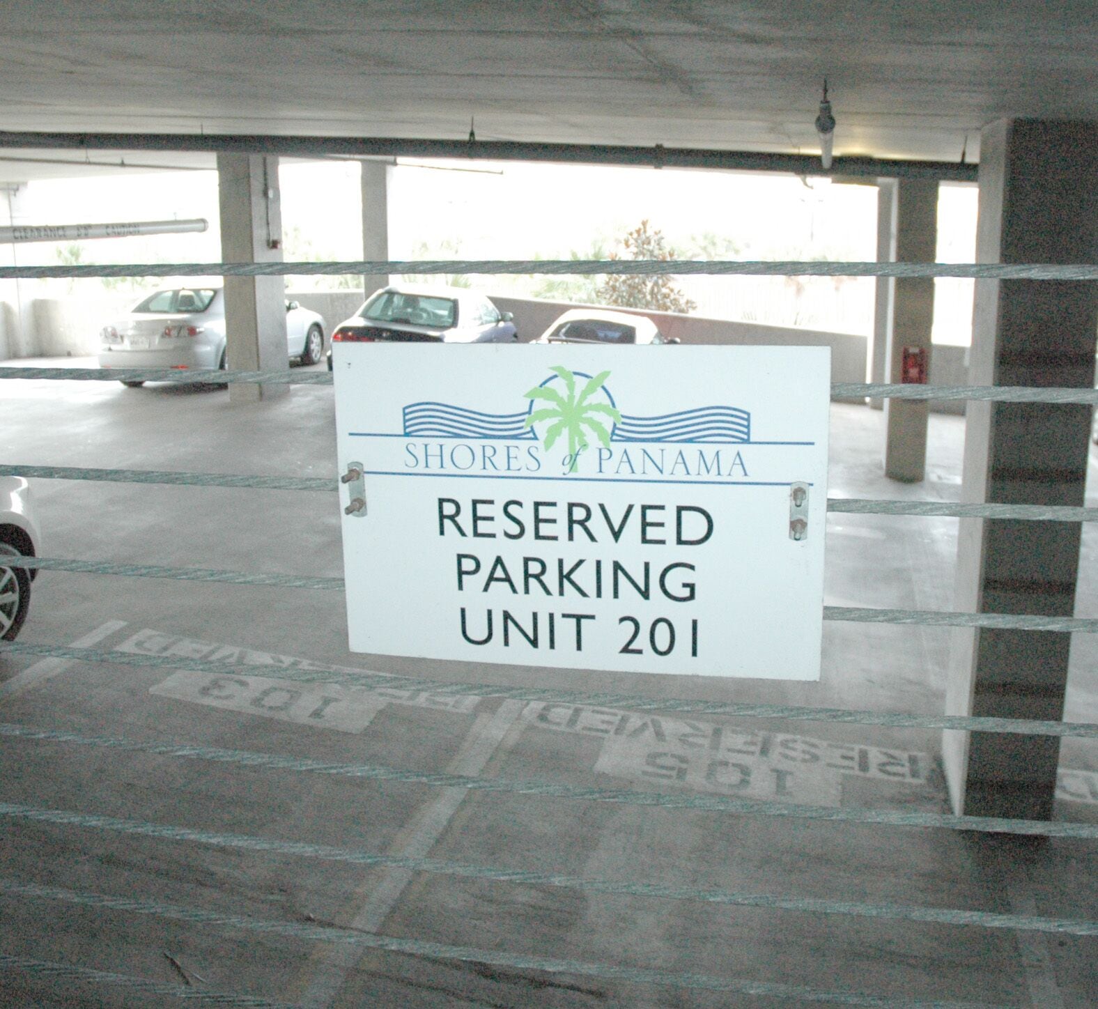 Señal que indica estacionamiento reservado para la unidad 201 en un garaje.