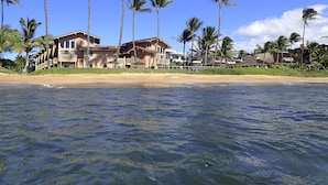 Una propiedad frente a la playa con varias edificaciones, palmeras y una playa de arena.