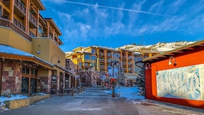 A hotel with multiple floors, outdoor seating, and a snow-covered ground. - Canyons View 20: 2 bed 2 bath, walk to the lift (Park City)