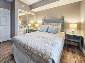 Ein Schlafzimmer mit einem großen Bett, zwei Nachttischen mit Lampen, einem Spiegel und einer Tür.