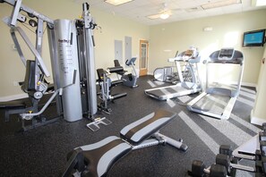 Une salle de sport équipée de divers appareils d’exercice, notamment des tapis de course, des appareils de musculation et des poids libres.