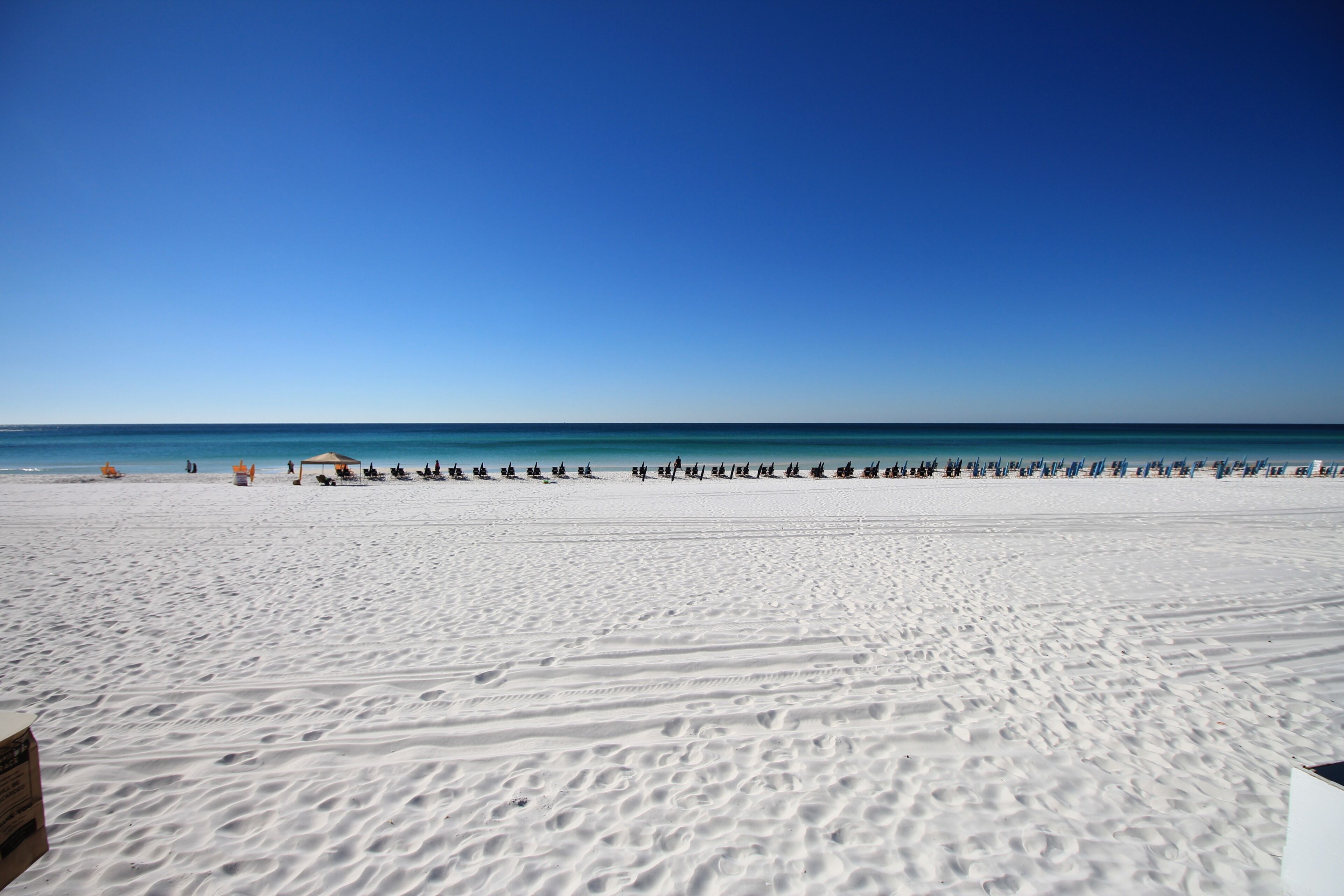 A wide sandy beach with a clear blue sky and calm sea.