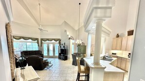 A spacious living area with a large sofa, a dining table, and a kitchen with a central island. - Villa close to beach Includes 6-Seat Golf Cart! 5257 TS (Miramar Beach)