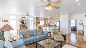 A spacious living room with a blue sofa, a glass coffee table, and a ceiling fan. - Fabulous Gulf Front Home, Gated neighborhood, Double porches, Santa Rosa Beach (Santa Rosa Beach)