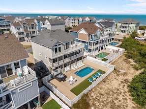 A beachfront residential area with multiple houses, a swimming pool, and a hot tub.