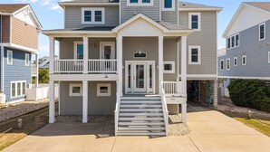 A two-story residential building with a front porch, a staircase leading to the entrance, and a visible address number. - Only 70 Steps to beach access! Elevator! Heated Pool!  Pets, Pool Table, Hot tub (Corolla)