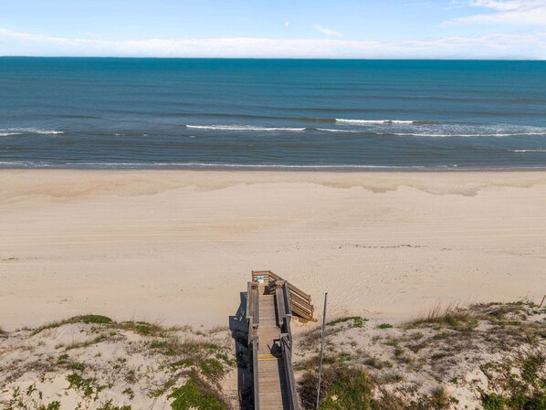 A beach with a wooden walkway leading to the water. - Only 70 Steps to beach access! Elevator! Heated Pool!  Pets, Pool Table, Hot tub (Corolla)