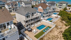 A multi-story residential building with a pool, outdoor seating, and a view of the ocean. - Only 70 Steps to beach access! Elevator! Heated Pool!  Pets, Pool Table, Hot tub (Corolla)