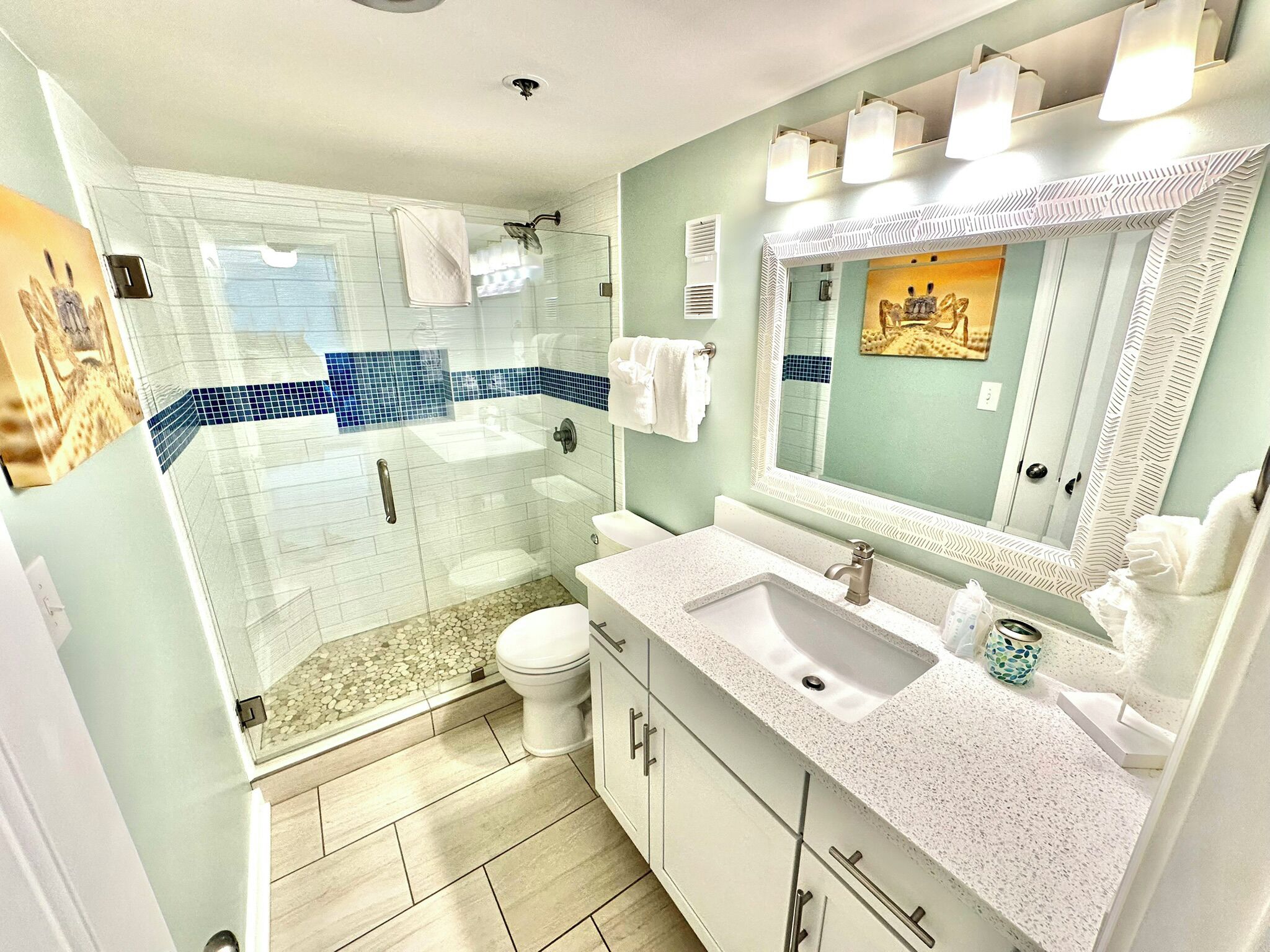 A modern bathroom with a glass-enclosed shower, a white sink, and a large mirror.