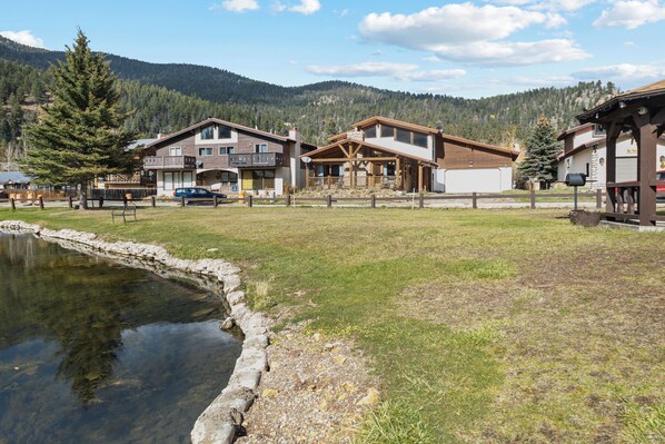 Ein Hotel am See mit einem von Steinen gesäumten Teich, einer Holzterrasse und Bergblick.