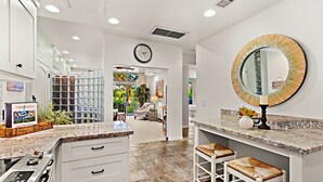 Una cocina moderna con encimeras de granito, armarios blancos y una isla grande con taburetes de bar.