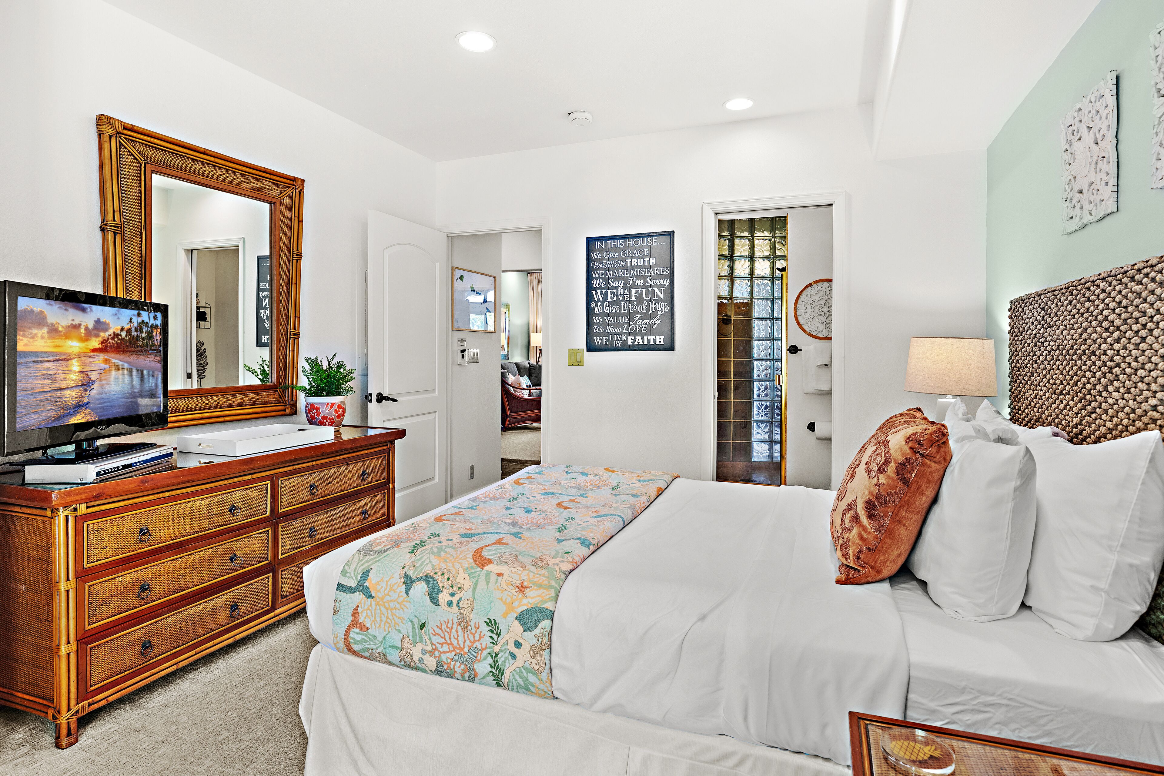 A bedroom with a bed, dresser, television, and decorative items.