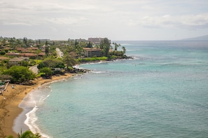 A coastal view with a beach, ocean, and buildings in the background.
