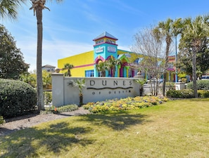 Un bâtiment aux couleurs vives, sur lequel on peut lire l’inscription « DUNES DE DESTIN ».