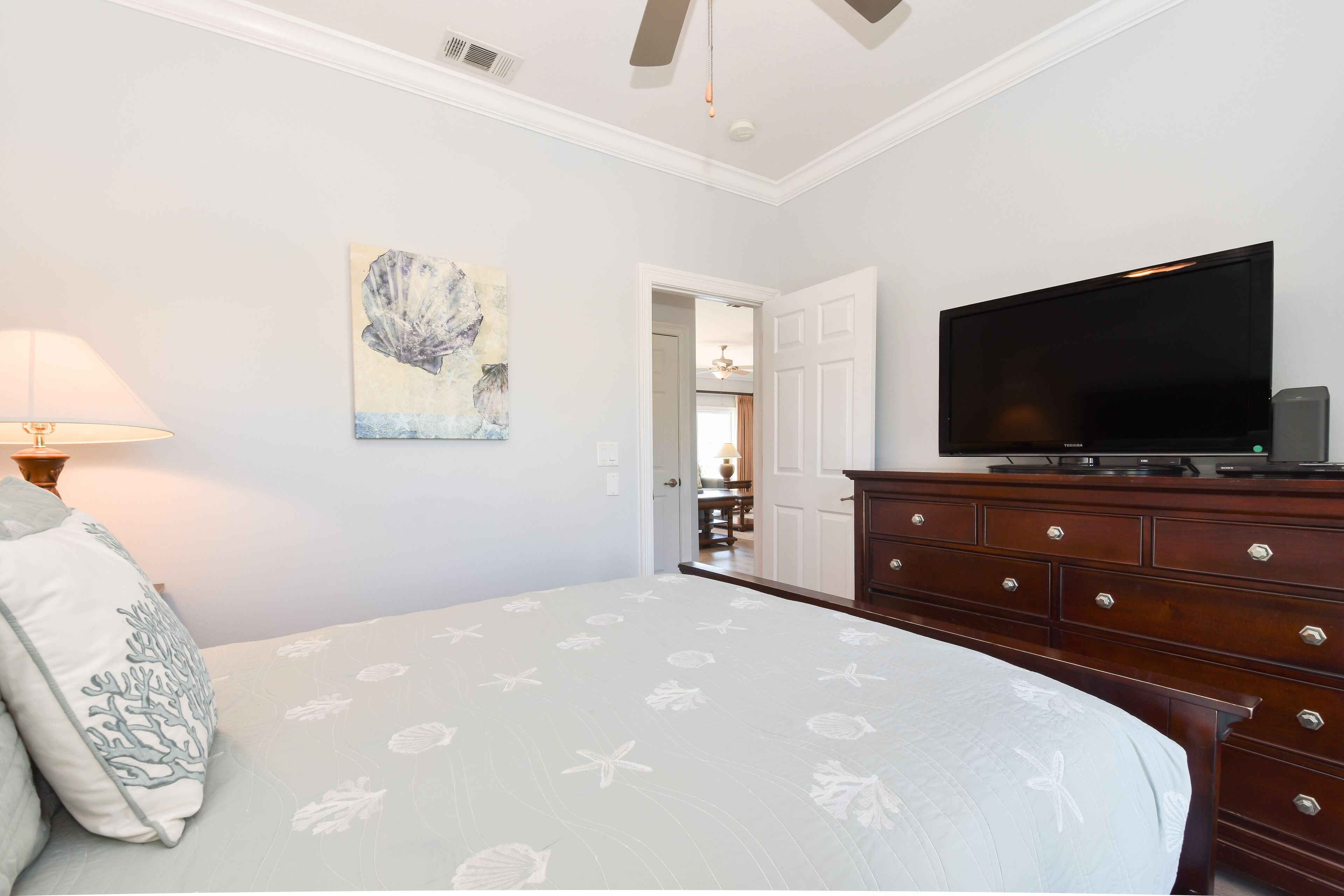 A bedroom with a bed, a TV, a dresser, and a painting on the wall.