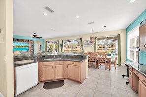 Enjoy meals in the kitchen with a central island and dishwasher, adjacent to a dining area with a table and chairs overlooking a scenic view.