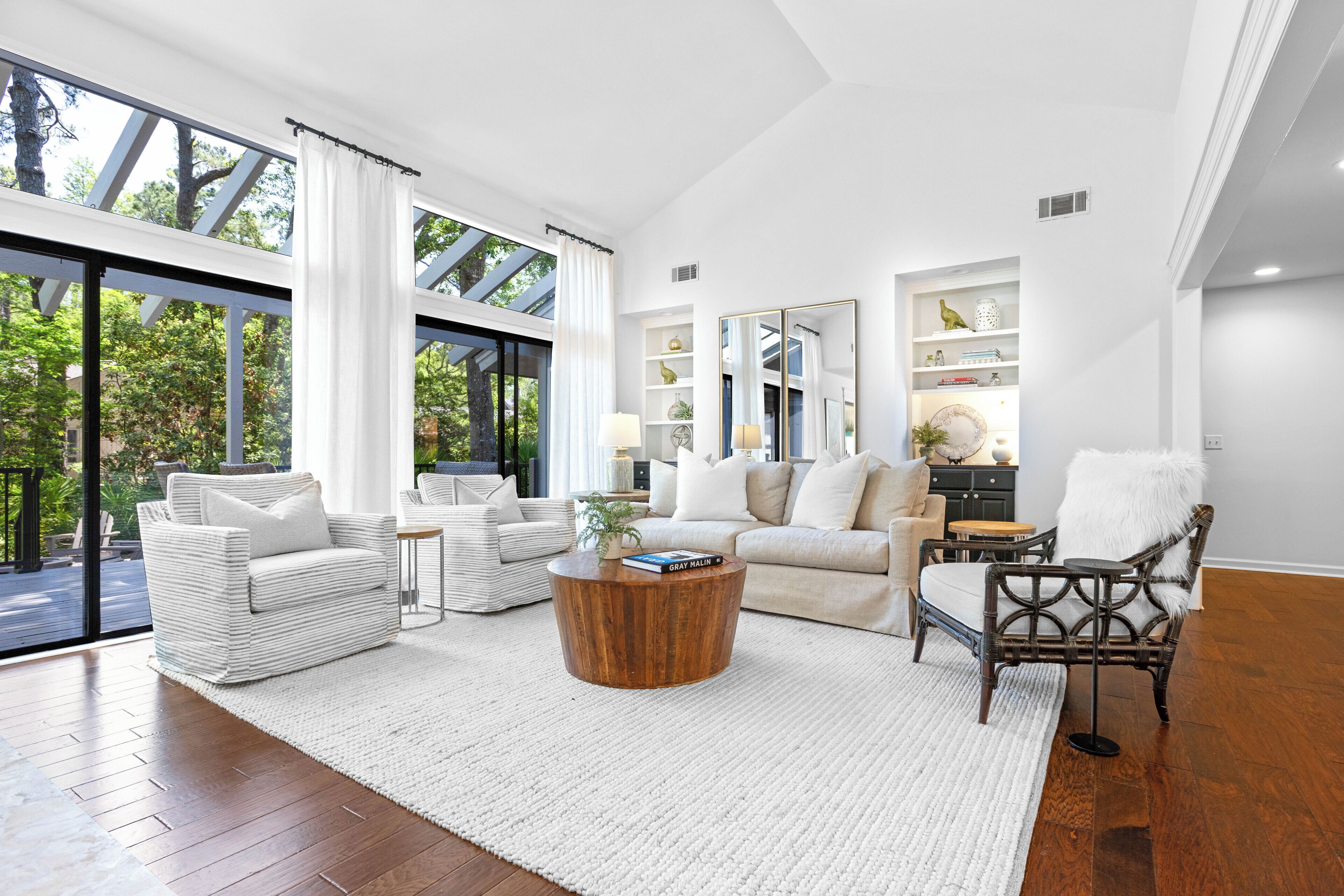 A spacious living room with a large window, a wooden coffee table, and a white sofa.