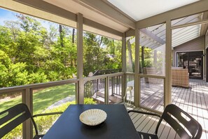 A covered outdoor patio with a table and chairs, overlooking a garden and a deck area. - 22 Hollyberry:  A BESTNEST by Beverly Serral (Hilton Head Island)