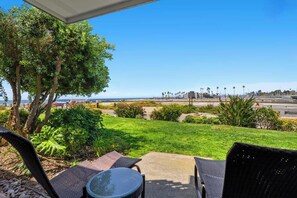A patio with outdoor furniture, a view of the ocean, and a landscaped garden.