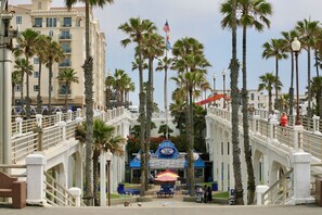 A coastal promenade with palm trees, a bridge, and a seafood restaurant.