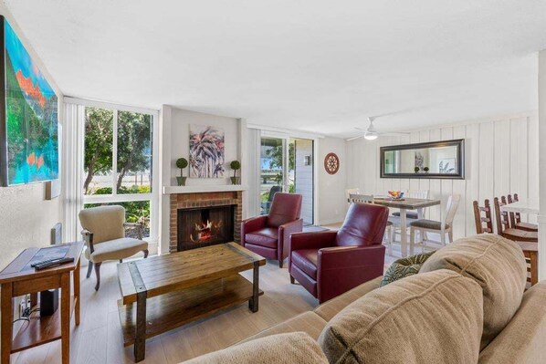 A living room with a fireplace, leather chairs, a wooden coffee table, and a sofa.