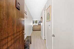 A hallway with a wooden door, a bench, and a sofa in the background. - Ground floor condo with grassy area, quick Beach Access, G33 North Coast Village (Oceanside)
