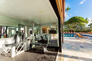 Une salle de sport équipée de matériel d’exercice, une piscine et une vue sur l’extérieur.