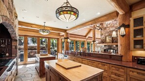 Una cocina amplia con armarios de madera, una isla grande y una chimenea de piedra.