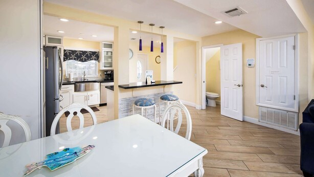 A modern kitchen with white cabinets, a black countertop, and a white dining table with chairs. - 356 Billfish🐟Beachside Townhome🐶Pet Friendly (Fort Walton Beach)