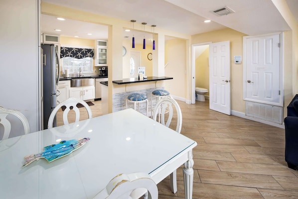 A modern kitchen with white cabinets, a black countertop, and a white dining table with chairs. - 356 Billfish🐟Beachside Townhome🐶Pet Friendly (Fort Walton Beach)