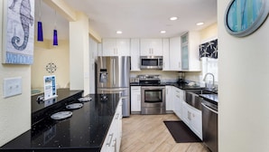 A modern kitchen with white cabinets, stainless steel appliances, and a black countertop. - 356 Billfish🐟Beachside Townhome🐶Pet Friendly (Fort Walton Beach)