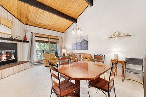 A cozy dining area with a wooden table and chairs, a fireplace, and a view of the outdoors.