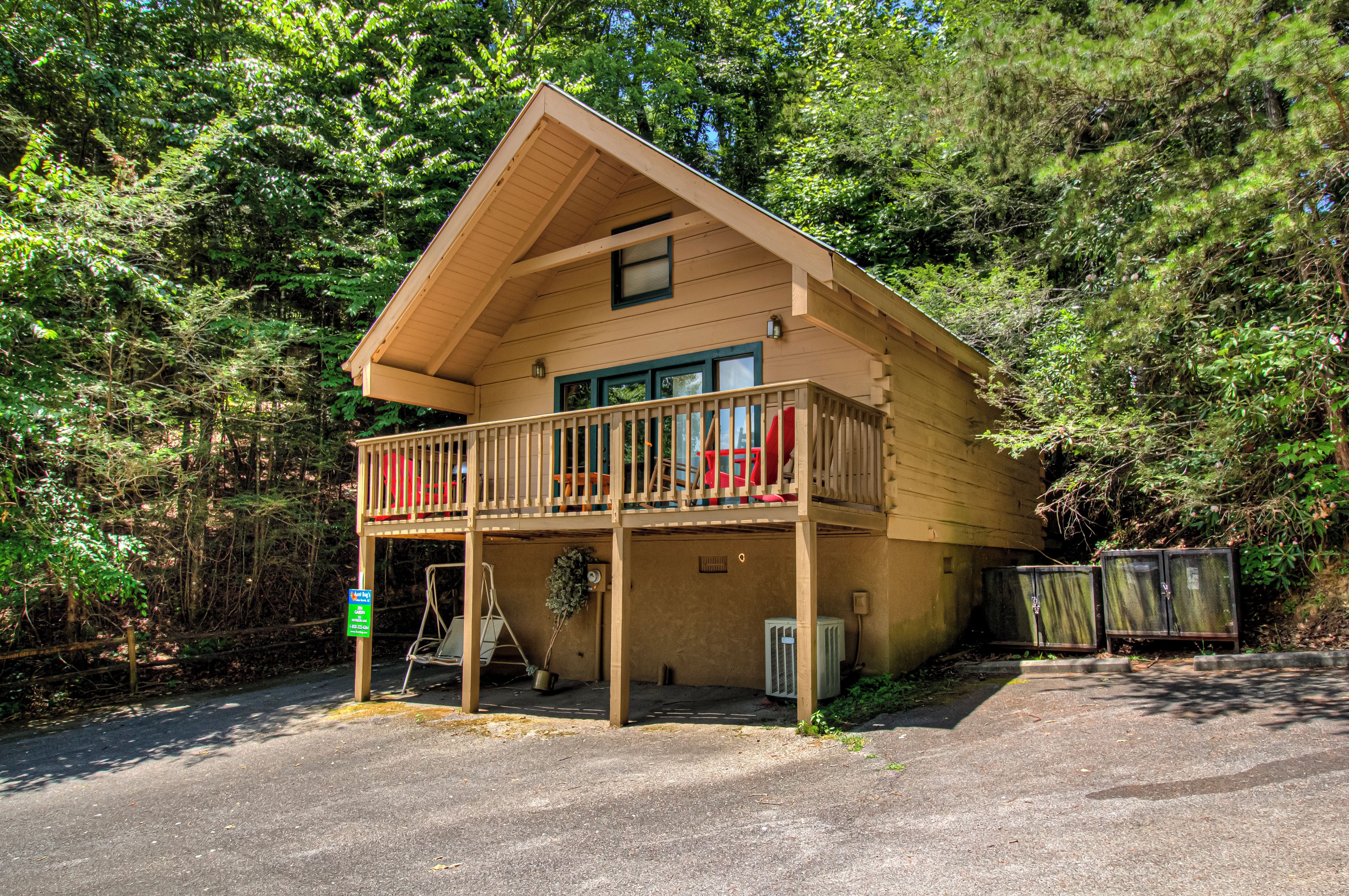Une cabane à deux étages dotée d’un balcon, entourée d’une forêt dense.
