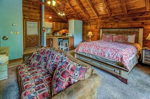 Ein gemütliches Blockhaus-Zimmer mit Bett, einer Sitzecke, einer Küchenzeile und einem Badezimmer.