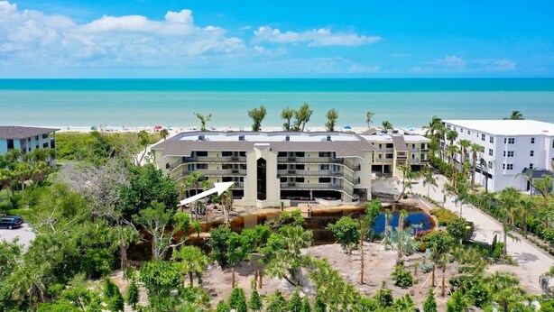 Ein Resort mit mehreren Gebäuden, einem Poolbereich und Blick auf den Strand.