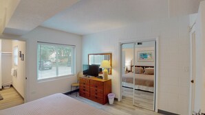 Un dormitorio con cama, cómoda, televisor y espejo.