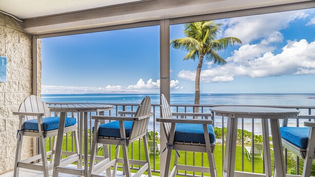 A balcony with chairs and a view of the ocean. - Kihei Beach #207 – Your Perfect Oceanfront Escape (Kihei)