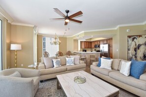 A living room with a sofa, coffee table, and a ceiling fan. - Spacious 4-bedroom beachfront end unit w/private balcony! (Destin)