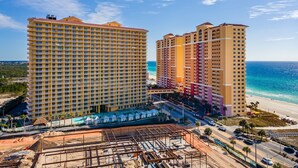Um hotel alto com vários andares, vista para a praia e um canteiro de obras em primeiro plano.