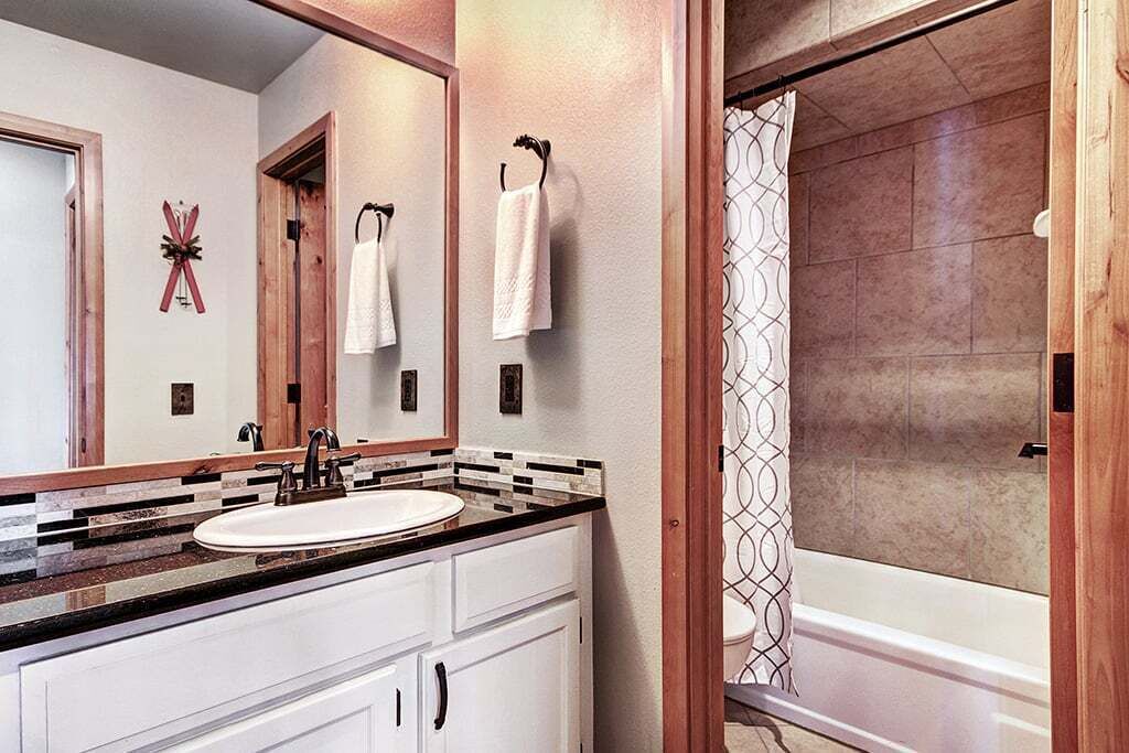 A bathroom with a white sink, a mirror, and a shower with a patterned curtain.