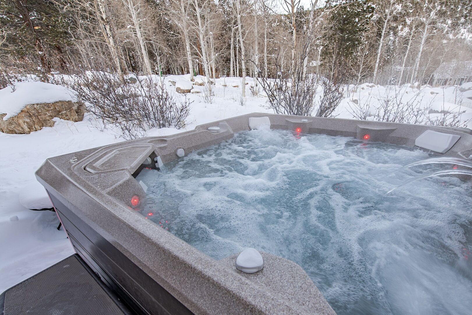 A hot tub surrounded by snow-covered ground and trees.