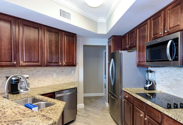 A kitchen with wooden cabinets, stainless steel appliances, granite countertops, and a built-in microwave.