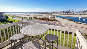 Un balcone con tavolo e due sedie vista spiaggia e porto turistico.