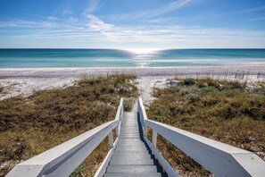 Eine Holztreppe führt zu einem Strand mit freiem Blick auf das Meer.