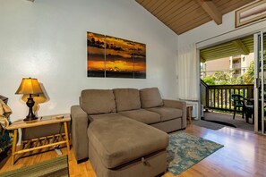 A living room with a sofa, a lamp, a rug, and a painting of a sunset.