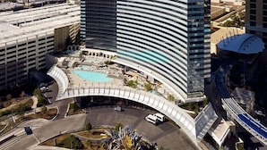 Ein modernes Hotel mit geschwungener Fassade, einem Schwimmbad und Blick auf die umliegende Stadtlandschaft.