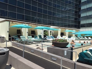 Relax by the rooftop pool surrounded by lounge chairs and umbrellas.