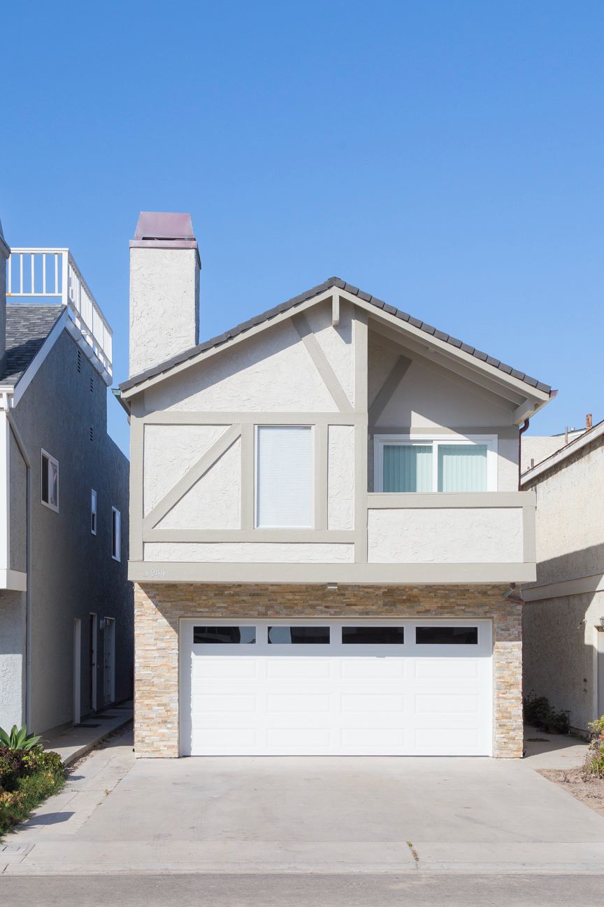 A two-story house with a garage, a balcony, and a chimney.